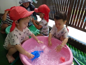 ひよこ組の子どもがタライの中の水を触って遊んでいます。