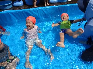 写真：プールの中で大の字になって浮く2人の3歳児