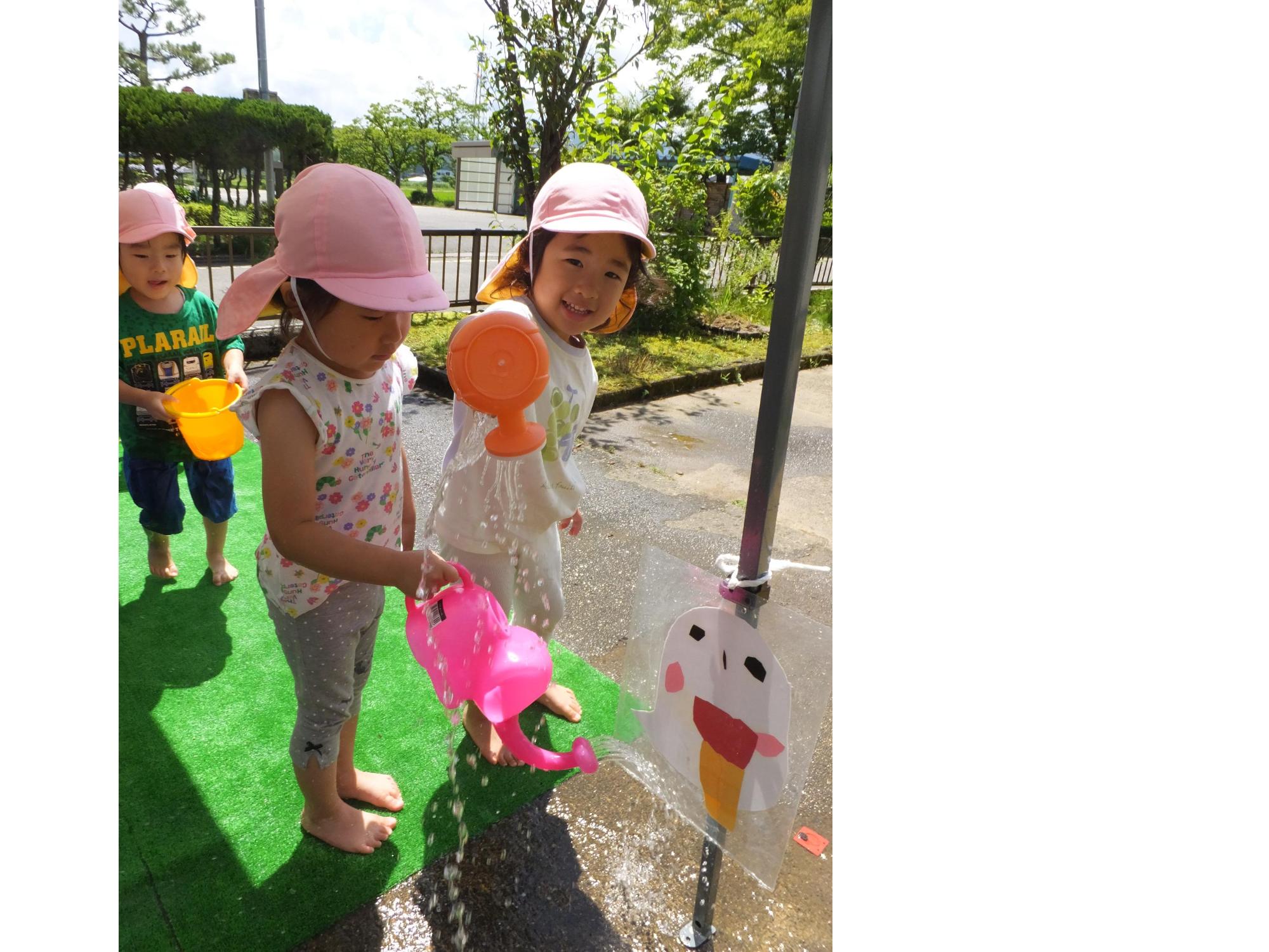 うさぎ組の子どもがじょうろを使って水遊びをしています。