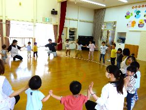 写真：輪になって並び、両隣の人と手のひらを合わせて押し合いっこをしている園児