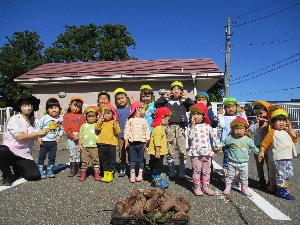 写真：収穫したサツマイモの前で、記念撮影をしている園児たち