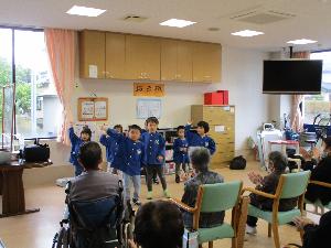写真：デイサービスセンターで踊りを披露する3・4・5歳児。利用者さんの手拍子に、ノリノリの様子で踊っています