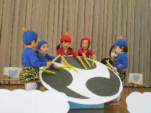 写真：かみなりさまの子になり切って、大きな太鼓をばちで打つ2歳児