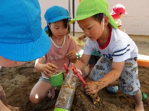 写真：ペットボトルを使って工夫しながら水路を作る年長児と年中児