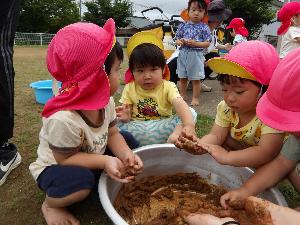 写真：タライの中の泥を手に取り、団子にしている2歳児