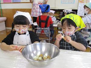 写真：ちくわを一口大の大きさにちぎってボウルに入れる2歳児