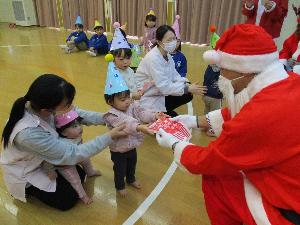 サンタクロースからプレゼントを手渡してもらう0・1歳児