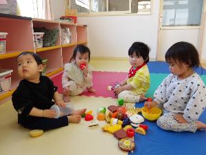 写真：0・1歳児4人おままごとセットを囲んで遊んでいるところ