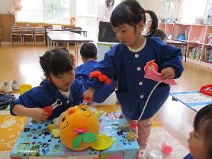 写真：お人形の口に道具を当てて治療ごっこをする2人の女の子