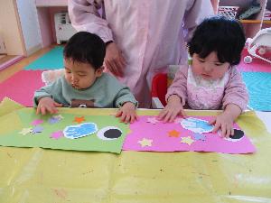 写真：こいのぼり型の画用紙に、星の模様を貼る2人の1歳児