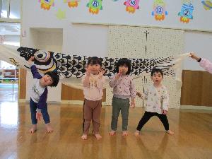 写真：黒色のお父さんこいのぼりの前でポーズをとる2歳児4人