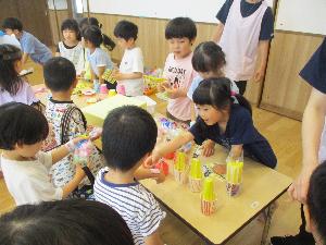写真：手作りおもちゃを選ぶ男の子とお店屋さんをする年長児の女の子