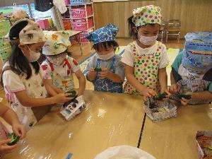 写真：エプロンをつけてピーマンの種取りをする年中児の男の子と女の子