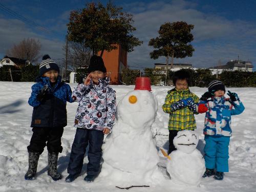 作った雪だるまと笑顔で写真を撮る年中児