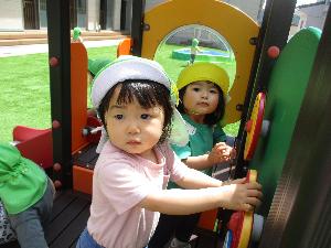 写真：ミニ園庭の遊具に付いているハンドルを持って遊ぶりす組の子どもたち