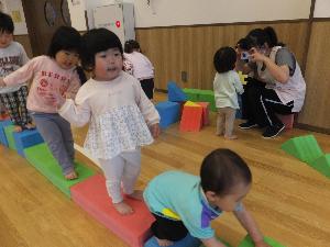 写真：遊戯室でソフト積み木を繋げて一本橋を渡るようにバランスをとりながら歩いて遊ぶうさぎ組の子どもたち