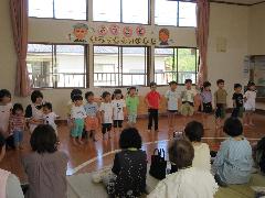写真：お遊戯室に並んだ子どもたちが、祖父母の前で歌をうたっています