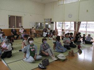 写真：祖父母の後ろに回り、肩を優しくたたいている子どもたち