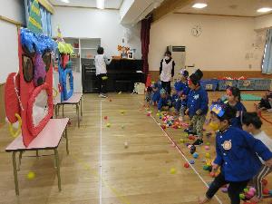 子ども達が、段ボールで作られた大きな鬼に向かって新聞ボールを投げて鬼退治をしている写真