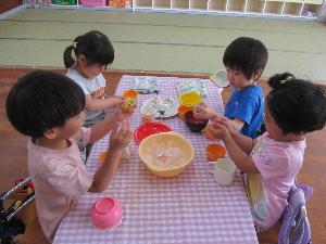 写真：3歳児4人が氷をコップやお皿に乗せたり、氷に触れて楽しんでいるところです