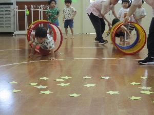 写真：2歳児が七夕のゲームでミニトンネルをくぐっているところです。その先には星形に切り抜かれたカードが並んでいます