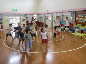 写真：全園児が遊戯室に集まり、元気よく手を挙げてエビカニクスの踊りを踊っているところです