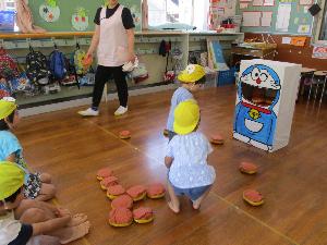 3歳児2名がドラえもんの口にどら焼きを入れるゲームをしています
