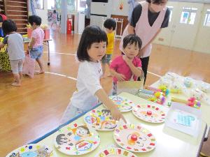 写真：3歳児がお祭りごっこのおもちゃ屋さんでおもちゃを選んでいるところです