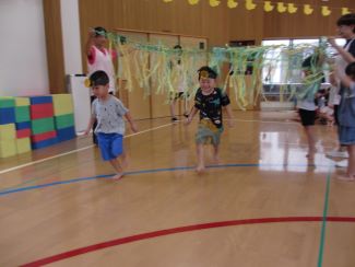 写真：ぱんだ組の子どもたちの障害物競争。ぶら下がったスズランテープをくぐり、走り出しているところ