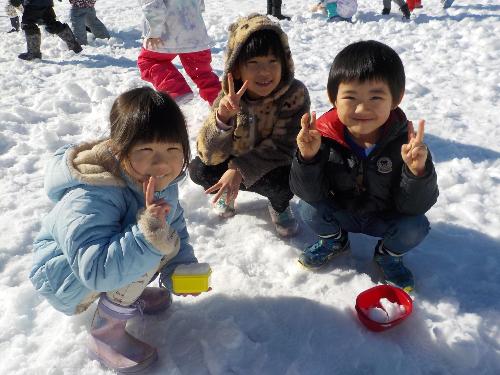 積もった雪でおままごとをするこどもたち