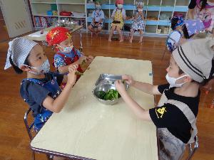 写真：4歳児がピーマンを一口サイズにちぎっています。