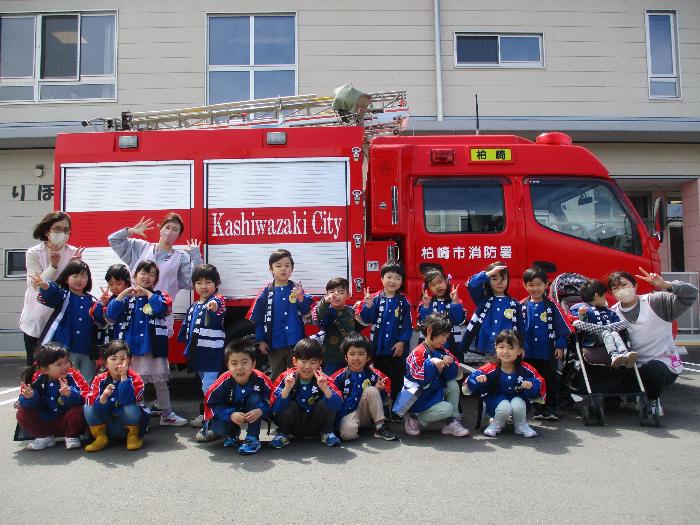写真：幼年消防の法被を着て、消防車の前に並んだらいおん組の年長児