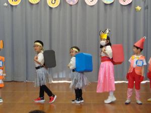 写真：年長児が劇の中で背負ったランドセルを観客に向けているところ