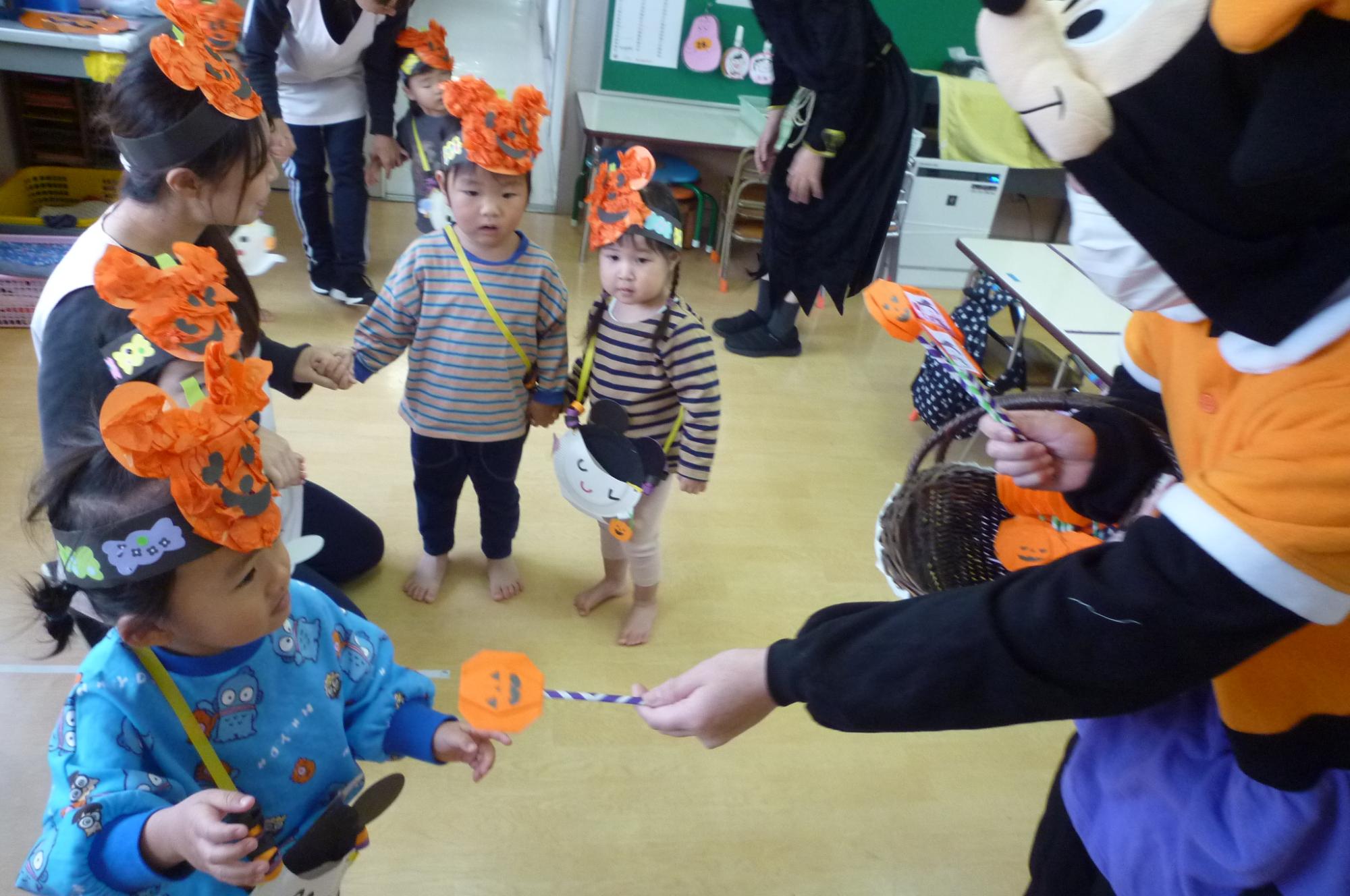 写真：ミッションをクリアし、かぼちゃおばけの折り紙がついたステッキをもらう子どもたち。