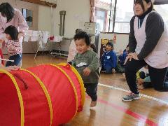 七五三のお祝いの行事でひよこ組の子どもが、トンネルをくぐるゲーム遊びに参加している写真