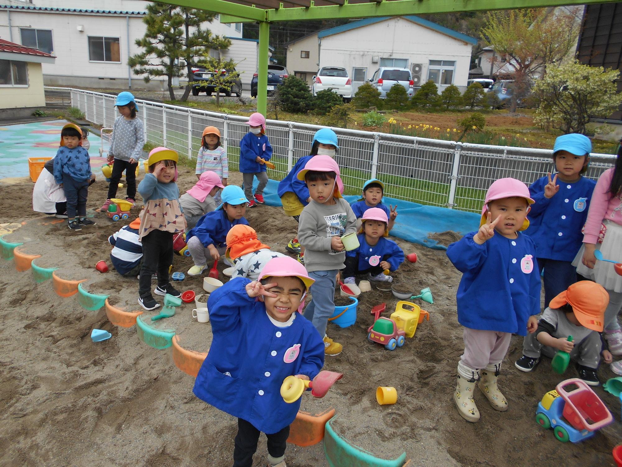 うさぎ組ときりん組が砂場で遊んでいる写真