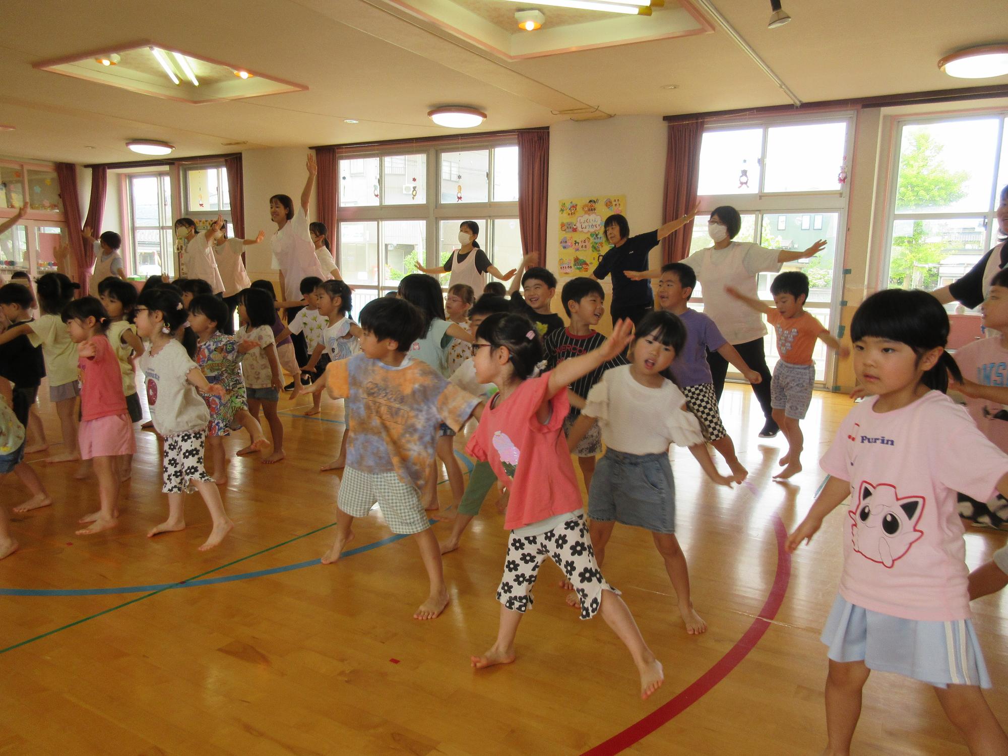 写真：フラミンゴのように、片足立ちをし、両手を広げてバランスを取る子どもたち。この後も動物にまつわる体操を楽しみました。