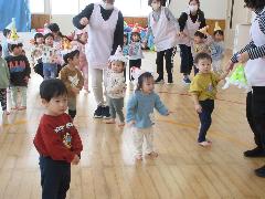 写真：小さなクラスの子が三角帽子をかぶり、曲に合わせて踊っています。
