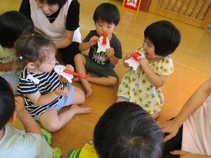 写真：おばけの形をした吹き戻しを吹いて遊ぶ2歳児たち