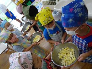 写真：バケツリレーのように、5歳児が切った野菜を隣の子に渡し、給食室に運んでいる様子