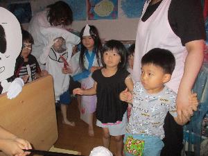 写真：5歳児のお化けに驚きながらお化け屋敷を進んでいく3歳児。一緒に回る保育士の手をしっかり握っています