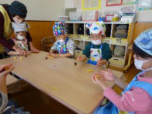 写真：保育室で3歳児の子ども4人がクッキー生地を手に持ち、成型しているところ