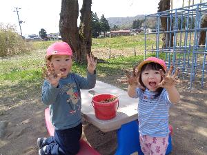 写真：砂のたくさんついた手を大きく開き、笑顔でその両手を見せている2人の園児