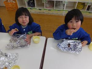 写真：保育室で2人の子どもが着席して、自分で作ったクッキーを笑顔で食べています