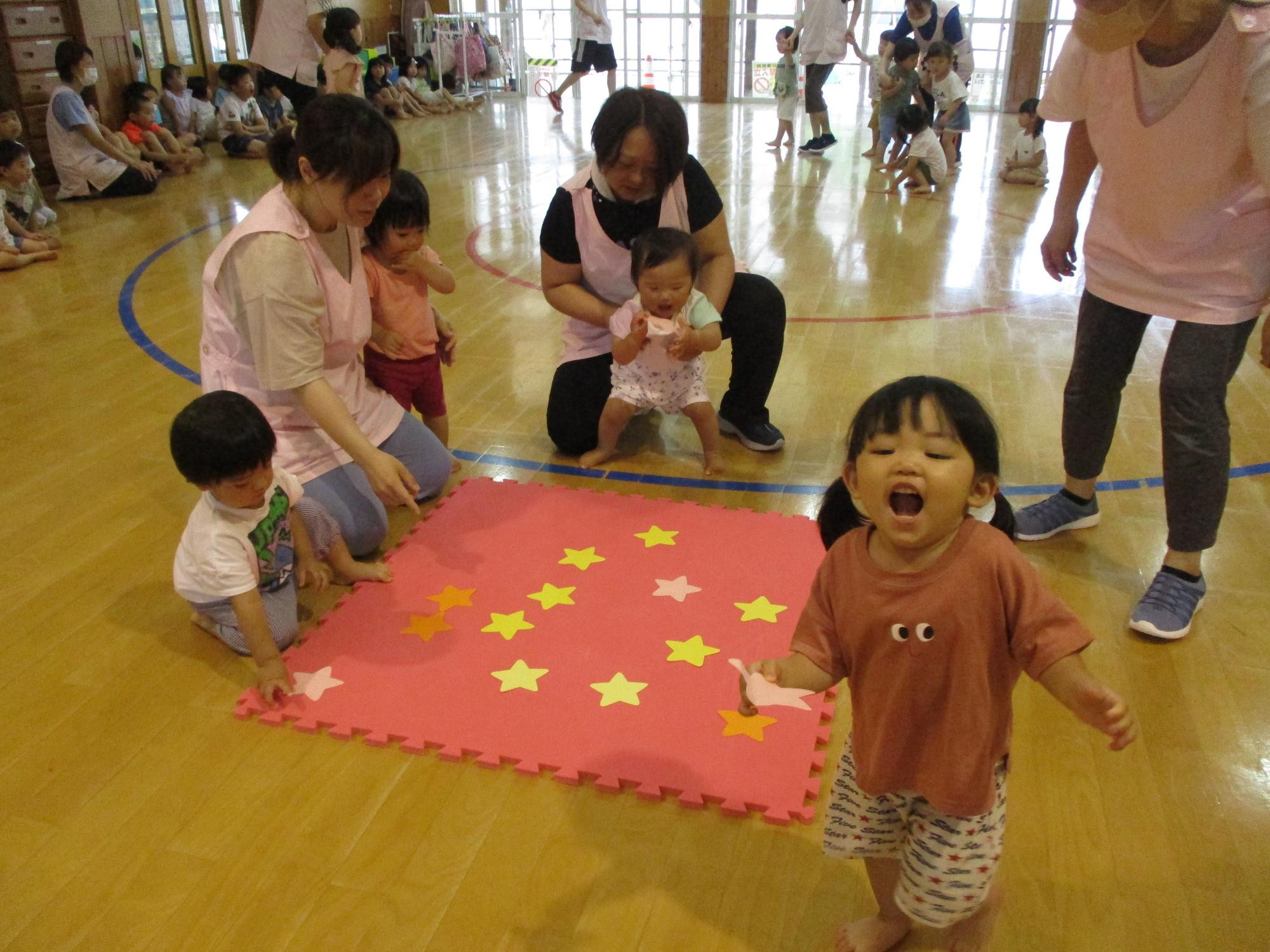 写真：0・1歳児が、床に置いてある星型のカードを選んでいる様子