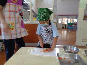 写真：年長児がニンジンを包丁で切っています。