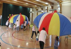 写真：職員と一緒にバルーンの裾を持ち、大きく膨らませている2・3歳児