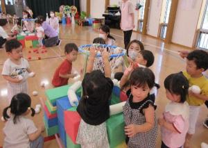 写真：子どもたちが背伸びをすると手が届くほど低く設置されたかごに、集めてきた玉を入れている1歳児たち