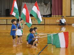 写真：6人の年長児がフラッグを持って整列し、ポーズをとっています