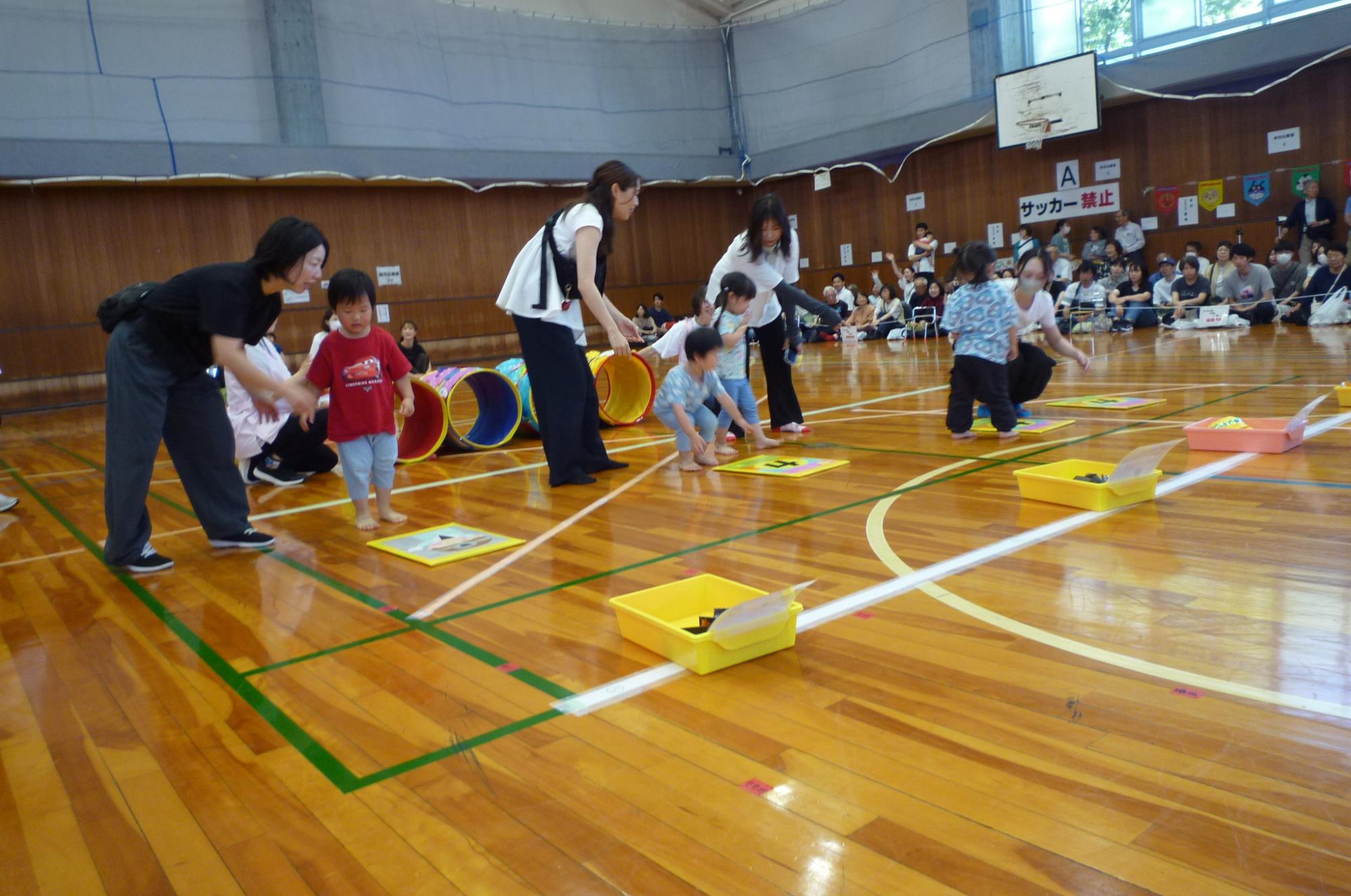 写真：親子で障害物レースをしているぱんだ組。ミニトンネルをくぐって、カードをめくろうとしています。